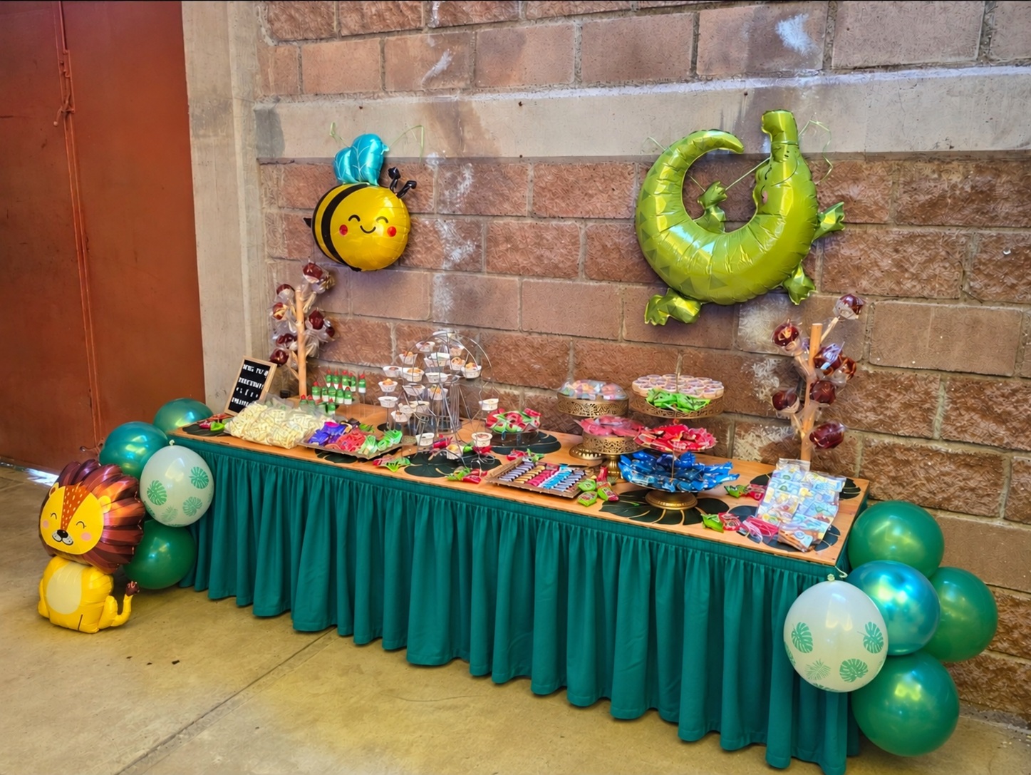 Mesa de dulces de Pom-Pomme con mantel turquesa y globos en los extremos
